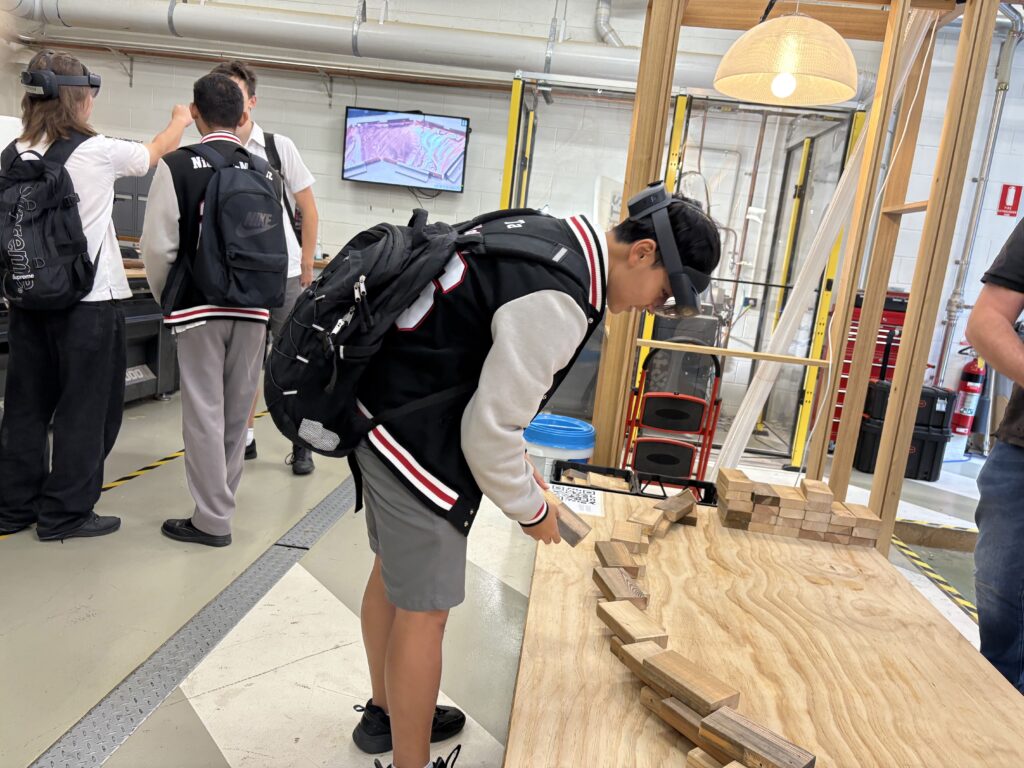 A student is wearing AR goggles and constructing a curved wall in the alternate reality
