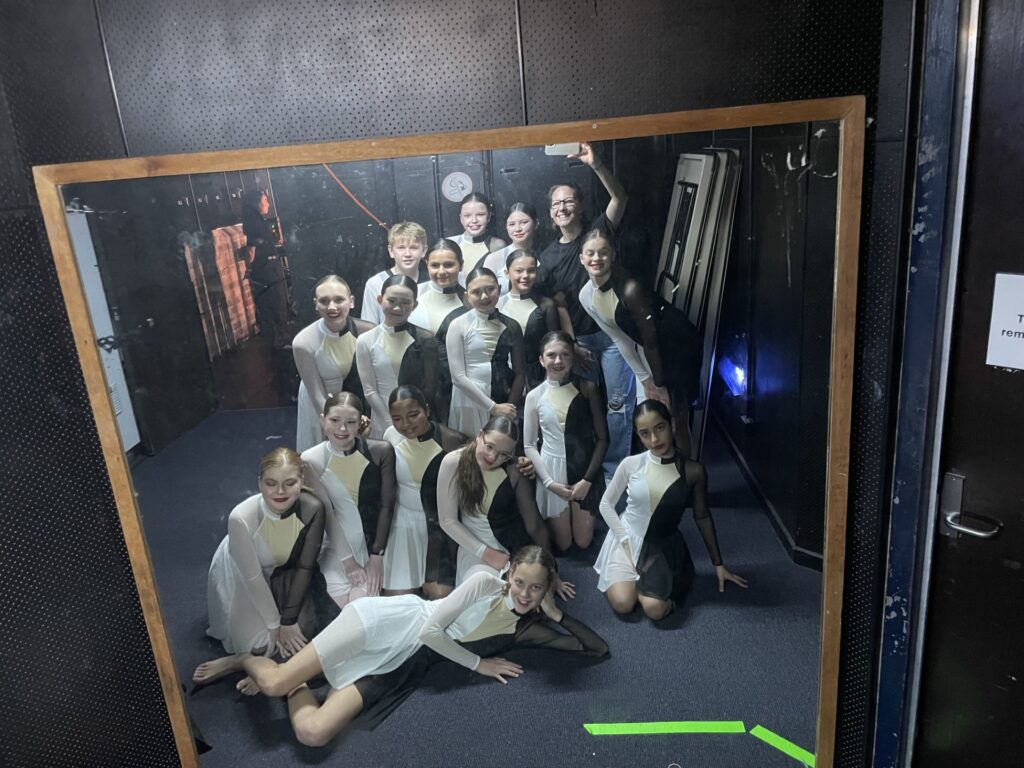 Celebrating a successful performance, students reflect teamwork, dedication, and achievement backstage.