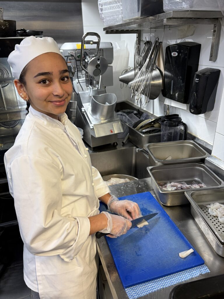 Demonstrating precision and professionalism, this student builds confidence through hands-on culinary experience.